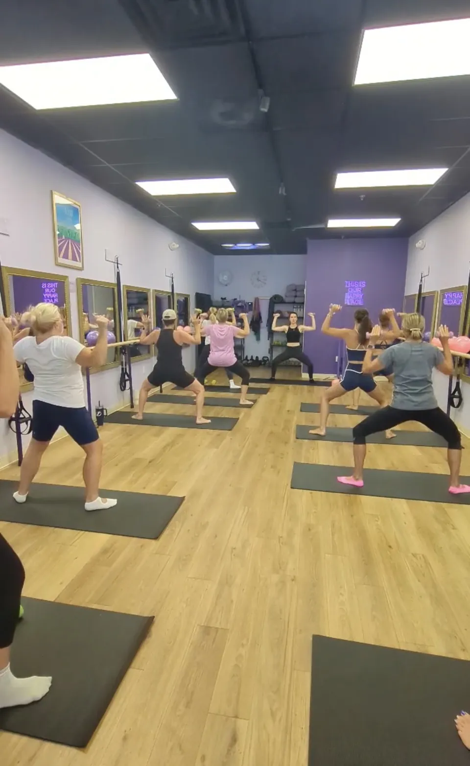 Barre class holding standing squats with arm work in the Ascendance studio