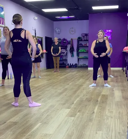 Instructor demonstrating a standing barre position for the class