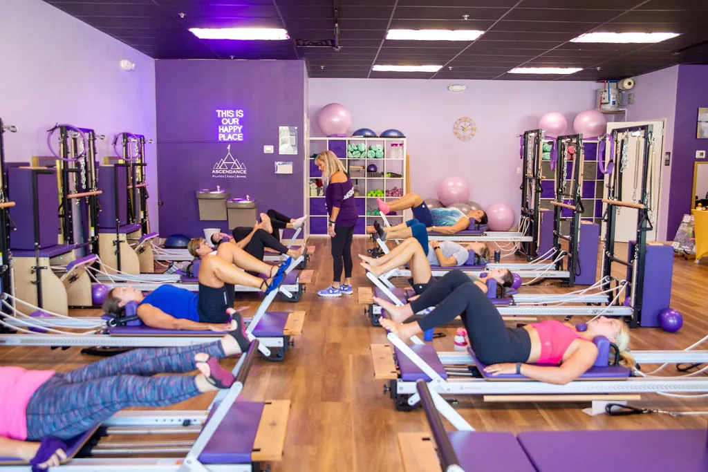 Instructor walking the Reformer room during a full group class at Ascendance