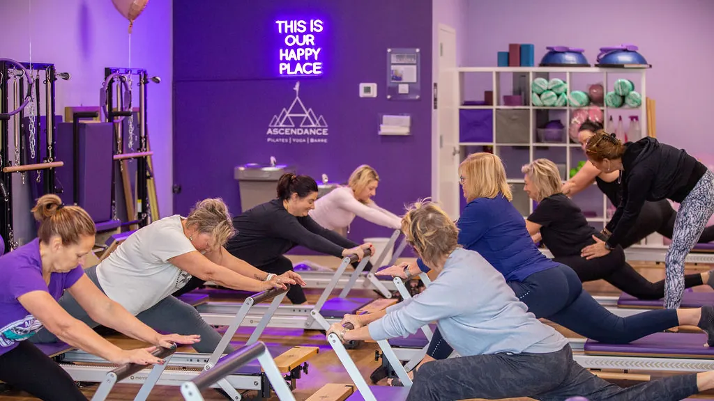 Group Reformer class stretching together beneath the &ldquo;This is our happy place&rdquo; sign at Ascendance in Fernandina Beach