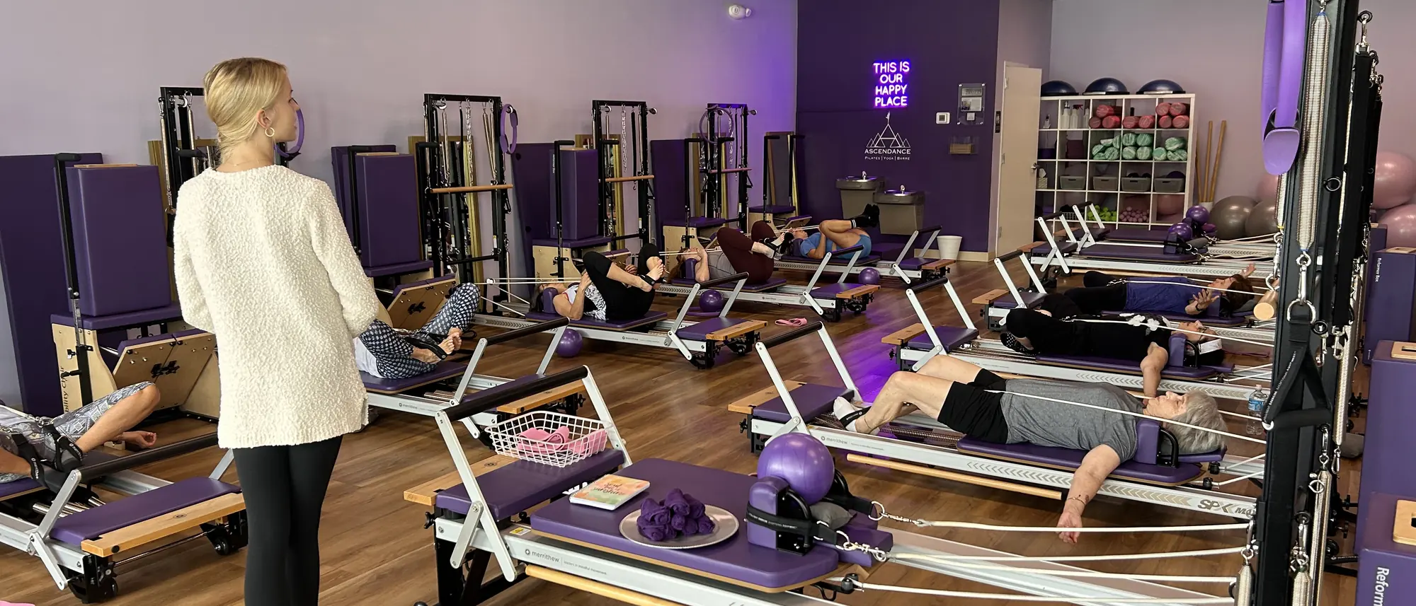 An Ascendance instructor walking the room and guiding a small-group Reformer Pilates class