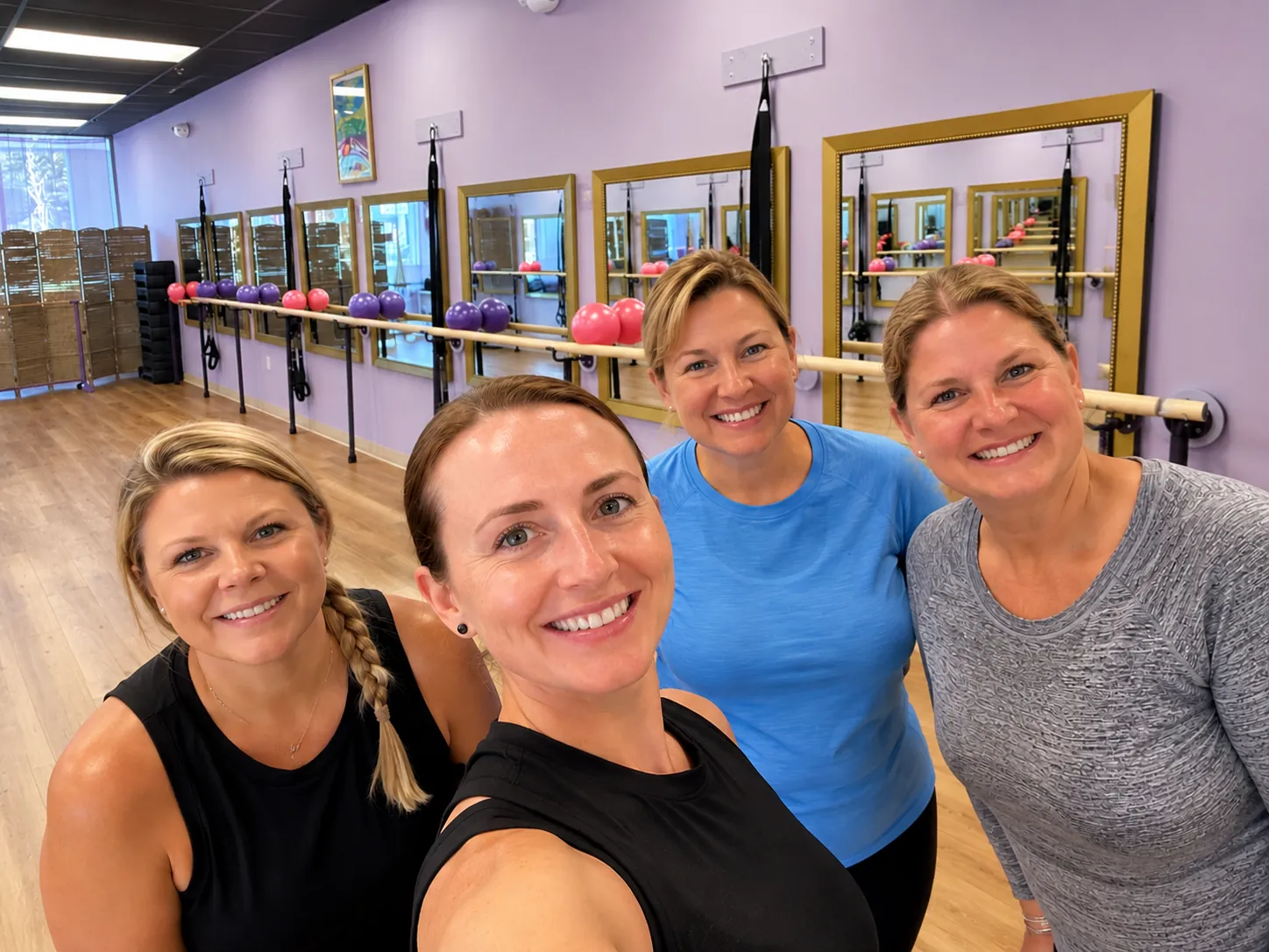 Four friends taking a selfie in the Ascendance barre studio during a private group class