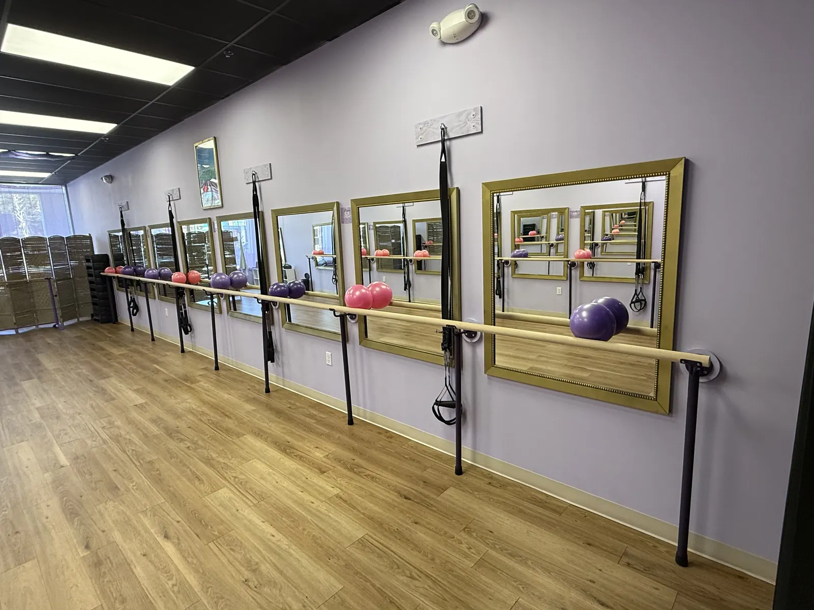 Fitness Classes studio at Ascendance with ballet barres, gold-framed mirrors, suspension straps and a wood floor